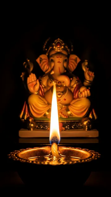 Ganesha Statue With Sacred Diya Flame In Dark