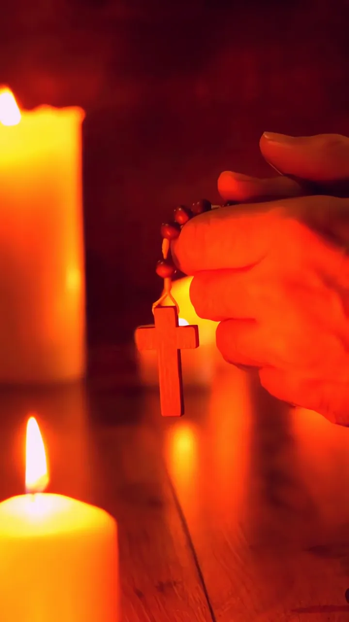 Hands Holding Rosary Cross With Warm Candlelight Prayer Scene