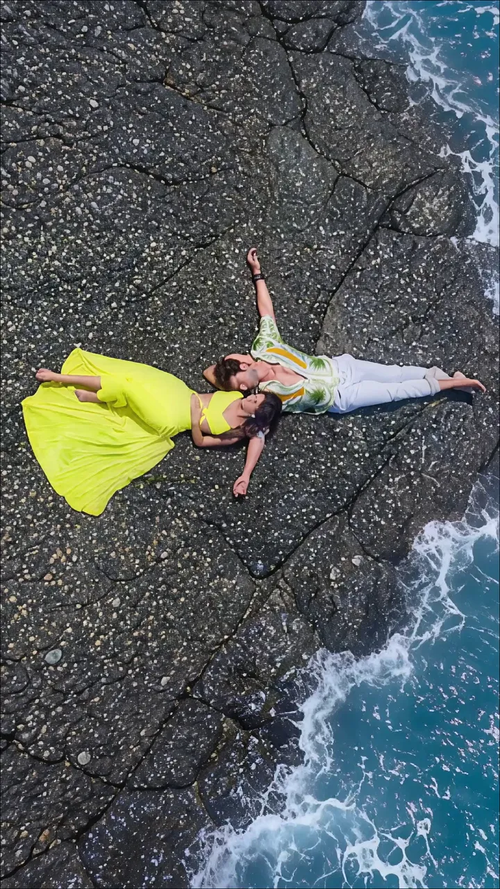 Couple Lying On Rocky Beach With Ocean Waves